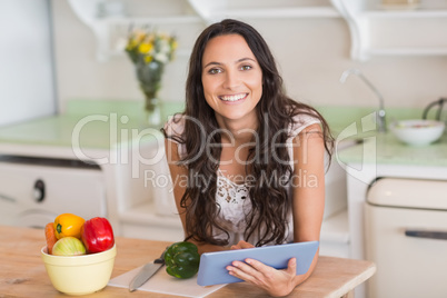 Pretty brunette using tablet pc and preparing salad