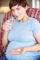 Pregnant woman taking a vitamin tablet