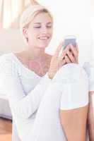 Smiling blonde woman texting with her mobile phone