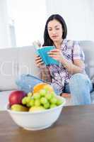 Pretty brunette reading a book on couch