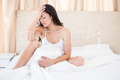 Pretty brunette with migraine on bed