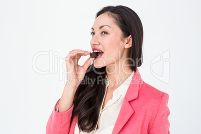 Smiling brunette eating chocolate