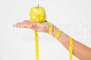 Woman holding apple with measuring tape