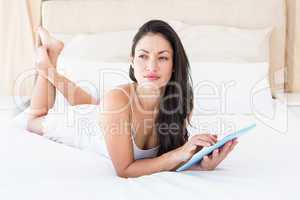 Pretty brunette touching tablet computer on couch