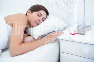 Woman sleeping in bed by spilt bottle of pills