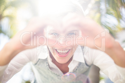 Pretty blonde woman smiling at the camera and doing heart shape