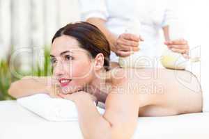 Brunette having massage with herbal compresses