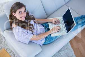 Happy brunette using her laptop on couch