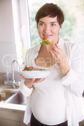 Pregnant woman having bowl of salad