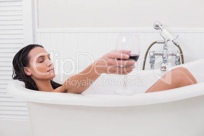 Pretty brunette taking a bath with glass of wine