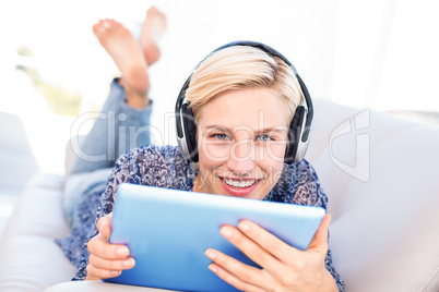 Pretty blonde woman lying on the couch and listening music