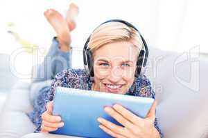 Pretty blonde woman lying on the couch and listening music