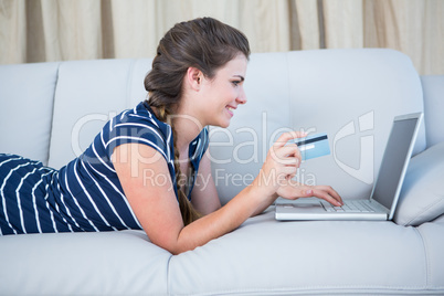 Pretty woman lying on couch doing online shopping