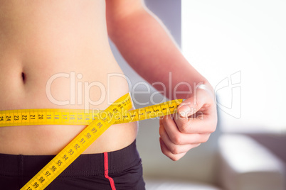 Slim woman measuring waist with tape measure