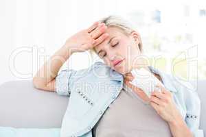 Sick blonde woman sitting on the couch