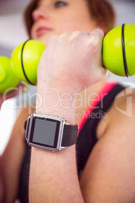 Fit woman lifting dumbbell sitting on ball