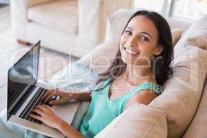 Pretty brunette using her laptop on the couch