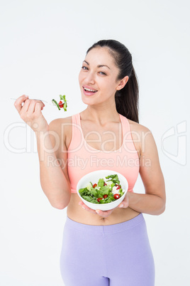 Smiling brunette eating salad