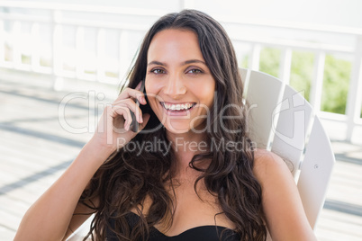 Pretty brunette sitting on a chair and calling with her mobile p