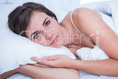 Sad brunette looking at camera in her bed