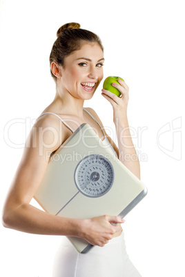 Slim woman holding scales and apple