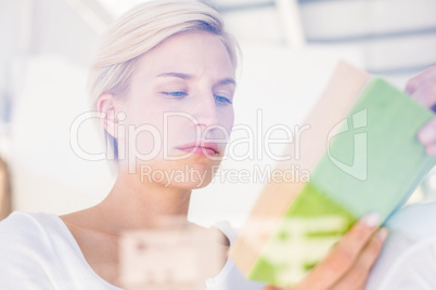 Thoughtful blonde woman reading a book