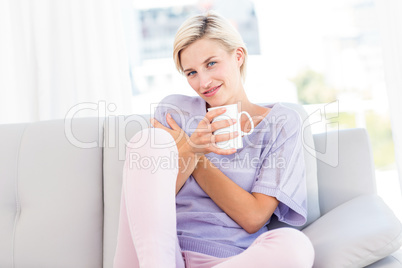 Pretty blonde woman relaxing on the couch and holding a mug Pretty blonde woman relaxing on the couch and holding a mug