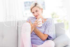 Pretty blonde woman relaxing on the couch and holding a mug