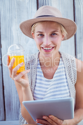 Pretty blonde woman using her tablet and holding orange juice