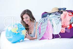Smiling brunette lying on bed looking her globe