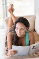 Pretty brunette reading magazine on the couch