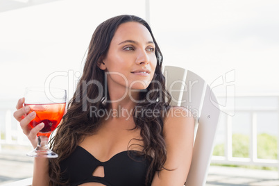 Pretty brunette sitting on a chair and drinking cocktail