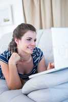 Happy  brunette on couch using her laptop