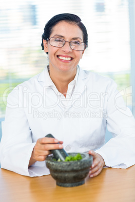 Scientist mixing herbs with pestle and mortar