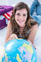 Beautiful woman with a suitcase pointing on a globe