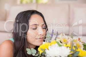 Pretty brunette lying on the floor and smelling the flowers