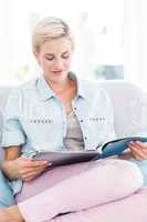 Pretty blonde woman reading a magazine on the couch