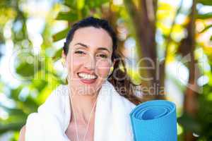 Fit beautiful brunette listening music and holding exercise mat