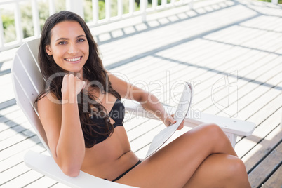 Pretty brunette sitting on a chair and reading magazine