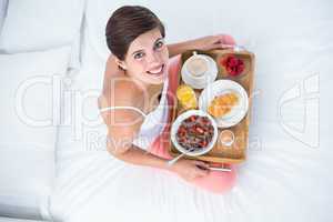 Happy brunette having her breakfast in bed
