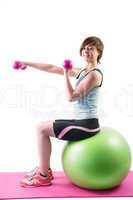 Pretty brunette exercising with dumbbells on fitness ball