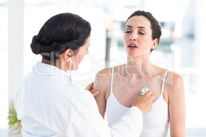 Doctor listening to patients chest with stethoscope