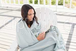 Pretty brunette sitting on a chair and reading a book