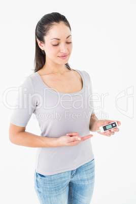Diabetic brunette holding blood glucose monitor