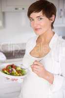 Pregnant woman having bowl of salad