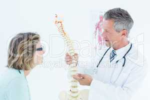 Doctor having conversation with his patient and showing spine mo