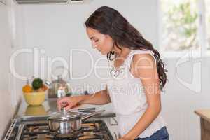 Beautiful brunette looking at saucepan