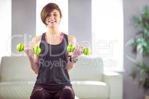 Fit woman lifting dumbbell sitting on ball