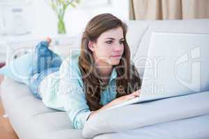 Focused brunette on couch using her laptop