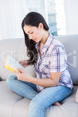 Pretty brunette reading a book on couch